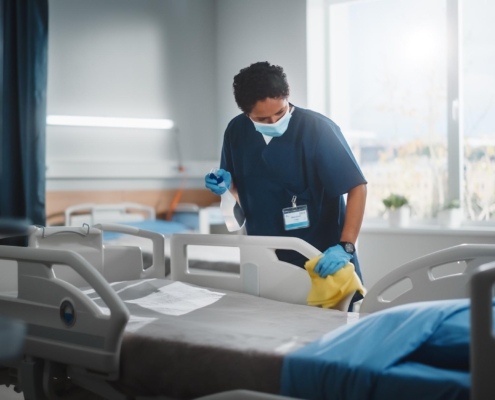 Person cleaning hospital room bed